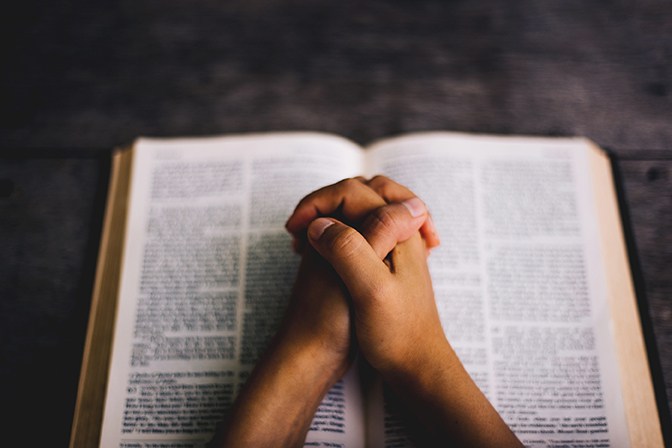 Stock hands praying over open bible