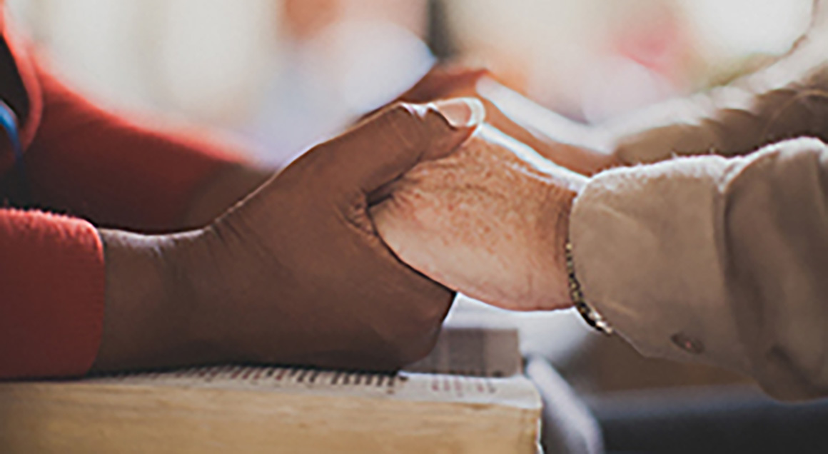 Stock holding hands over bible 1160x636