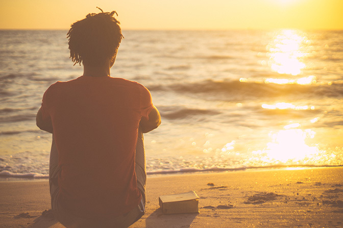 Stock man overlooking beach with bible