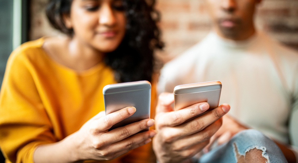 Two people looking at phones 1160x636